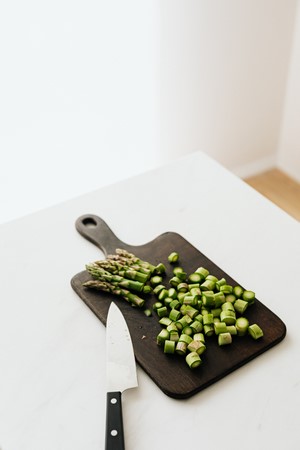 Chopped asparagus on cutting board near knife on table picture
